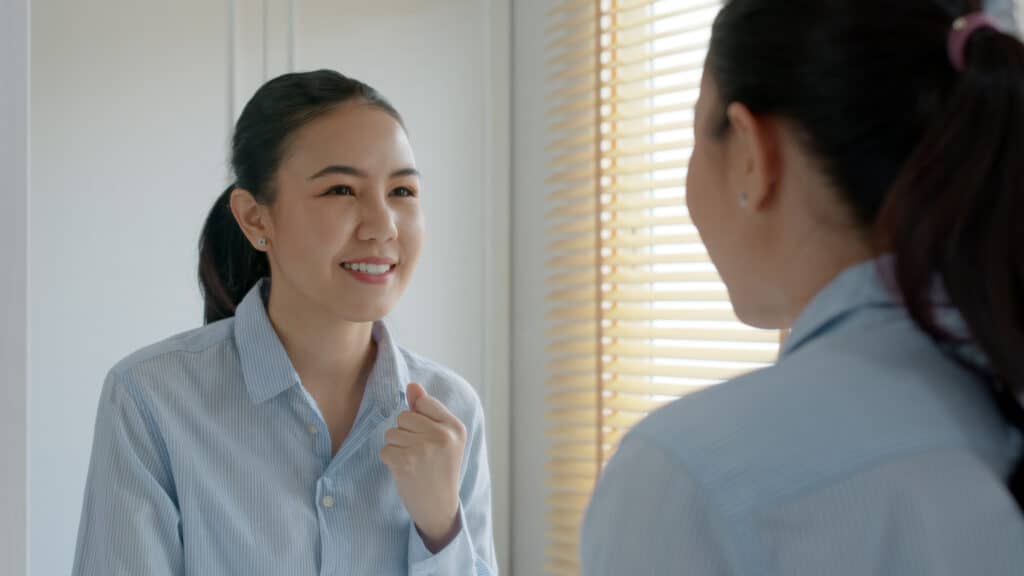 Femme qui se donne confiance en parlant dans le miroir